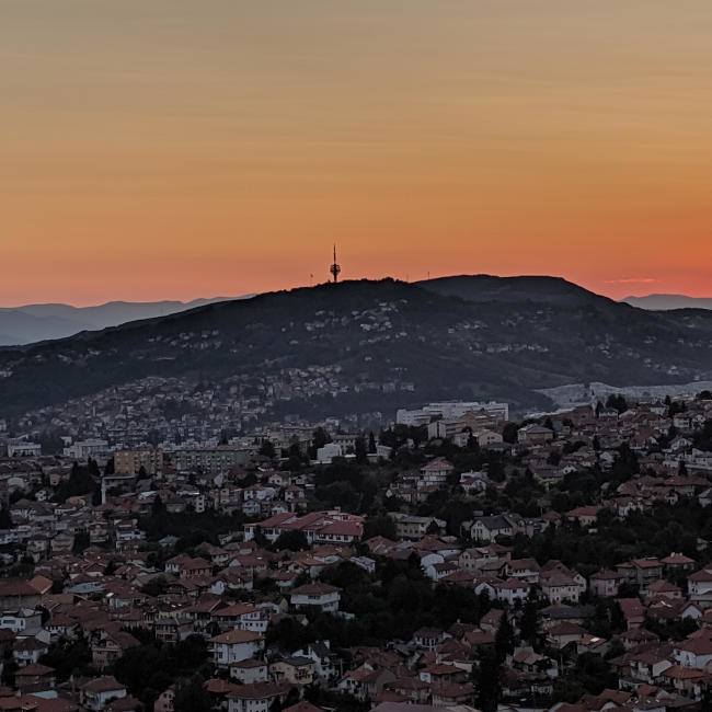 A view of Sarajevo's famous radio tower on a hill in the background at sunset