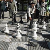 Elderly men play chess on an outdoor oversized board