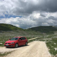 The deserted and unpaved road to Lukomir with a small car parked up