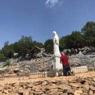 A man prays in front of a statue of the Virgin Mary at the Međugorje site
