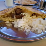 Ćevapi on a metal plate in somun bread with chopped raw onion