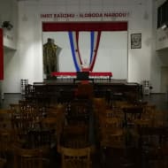 A snap from inside the AVNOJ museum, with chairs lined up infront of a stage. Death to facism is wriiten on the wall behind