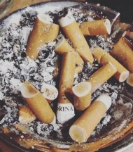 A full ashtray with a local brand, Drina, on one the used cigarette filters